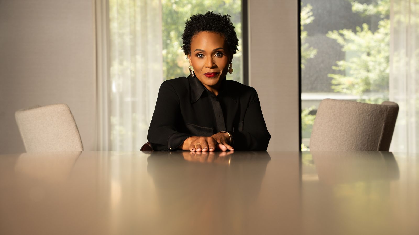 Cynthia Barnes at a boardroom table with empty chairs on either side.